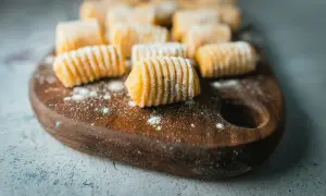 Gnocchi fatti in casa, pronti per essere cucinati. La gnocchi ricetta perfetta è a portata di mano, con questi morbidi e invitanti gnocchi su un tagliere di legno.