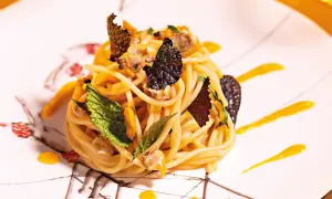 Spaghetti con frutti di mare, guarniti con foglie di menta e scaglie di tartufo. Un'idea su come cucinare la pasta in modo elegante.