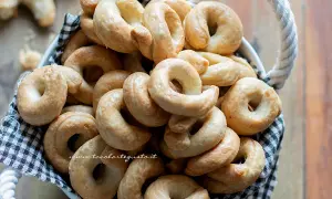 Un cesto pieno di taralli pugliesi ricetta originale, dorati e croccanti, pronti per essere gustati.