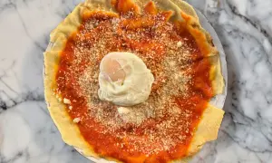 Piatto con pane carasau, salsa di pomodoro, formaggio grattugiato e uovo in camicia. Un'idea per gustose ricette.