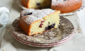 Una fetta di torta nua soffice, cosparsa di zucchero a velo, con un cuore di marmellata di frutti di bosco.
