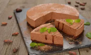 Deliziosa bavarese al cioccolato, spolverata di cacao e decorata con menta fresca. Un dolce invitante su una lavagna scura.