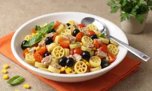 Un piatto invitante di pasta fredda saporita con tonno, pomodorini, olive nere e mais. Fresca e colorata, perfetta per l'estate.