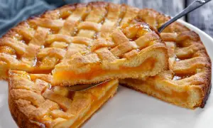 Deliziosa crostata senza glutine con ripieno di albicocche, una fetta sollevata da un coltello.