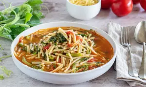 Piatto di pasta con i tenerumi asciutta, pomodoro e verdure fresche, pronto per essere gustato.