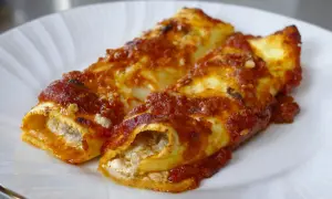 Due cannelloni di carne ripieni e ricoperti di sugo rosso, serviti su un piatto bianco.