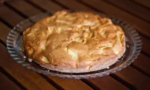 Torta di pane e mele alla trentina, dorata e invitante, su un piatto di vetro, pronta per essere gustata.