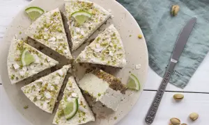Deliziosa cheesecake vegana con lime e pistacchi, guarnita con scaglie di cocco.