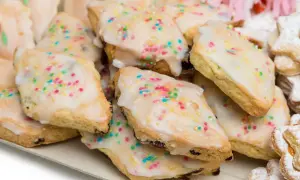 Un vassoio pieno di dolci sardi, biscotti ricoperti di glassa bianca e confettini colorati, perfetti per ogni occasione.