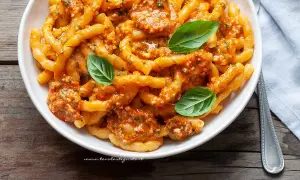 Busiate alla trapanese, pasta fresca con sugo rosso e basilico, un piatto ricco di sapori mediterranei.