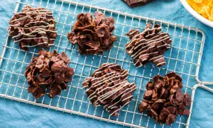 Sei deliziose rose del deserto al cioccolato, alcune decorate con glassa bianca, riposano su una griglia.