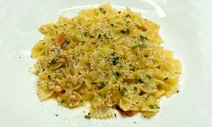 Farfalle condite con cubetti di salmone rosa, prezzemolo tritato e pepe nero. Un piatto di pasta al salmone invitante.