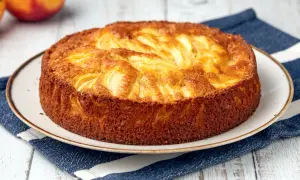 Una deliziosa torta di mele dorata, con mele a vista sulla superficie, servita su un piatto con un tovagliolo a righe blu.
