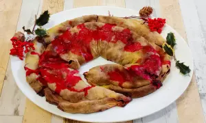 Dolce natalizio a forma di spirale, una rocciata umbra con glassa rossa e decorazioni di agrifoglio e bacche.