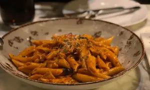 Penne al dente condite con una ricca crema di melanzane, guarnite con parmigiano e prezzemolo. Un piatto invitante per un pranzo gustoso.
