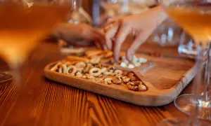 Un vassoio di legno con taralli e frutta secca, accanto a bicchieri di vino ambrato. Un momento di relax e gusto.