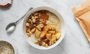 Una ciotola di avena per colazione con mele, frutta secca e burro di arachidi. Un pasto sano e gustoso.