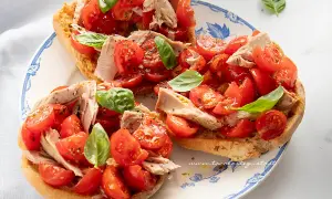 Friselle con pomodorini freschi, tonno e basilico, un piatto estivo leggero e gustoso.