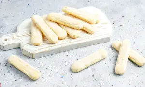 Savoiardi pronti per la ricetta del tiramisù, disposti su un tagliere bianco.