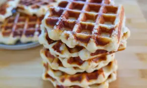 Una pila di waffle dorati, con la loro tipica griglia, che ricordano la waffle ricetta originale belga.