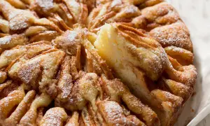 Una fetta di torta di mele morbidissima, cosparsa di zucchero a velo, con un aspetto invitante e casalingo.