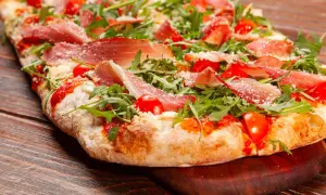 Pizza bianca con prosciutto crudo, pomodorini e rucola, cosparsa di parmigiano. Un'esplosione di sapori su un impasto soffice.