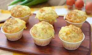 Sei muffin salati dorati, guarniti con semi di sesamo e formaggio filante, pronti per essere gustati.