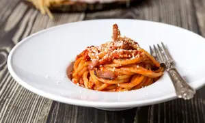 Un piatto di spaghetti alla amatriciana, con guanciale croccante e un tocco di cipolla per una ricetta originale.