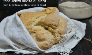 Pane senza lievito di birra, dorato e fragrante, avvolto in un panno bianco. Accanto, un vasetto con lievito madre alla mela.