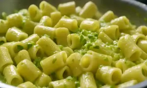 Rigatoni conditi con una cremosa salsa verde, un delizioso piatto di pasta e zucchine alla napoletana.