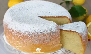 Torta al limone morbidissima e profumatissima benedetta, cosparsa di zucchero a velo. La fetta tagliata rivela la sua sofficità.