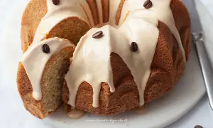 Una deliziosa torta al caffè, con glassa chiara e chicchi di caffè come decorazione. Una fetta è stata tagliata, rivelando l'interno soffice.