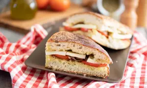 Pane cunzato con pomodoro, formaggio e acciughe, pronto per essere gustato.