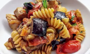 Fusilli con pesce spada, melanzane, pomodorini e basilico, un piatto estivo saporito.