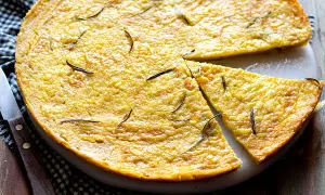 Dorata farinata di ceci in padella, guarnita con rosmarino fresco, pronta per essere gustata.