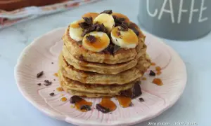 Pancake banana e yogurt, una pila golosa con scaglie di cioccolato e sciroppo d'acero.