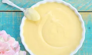 Crema pasticcera ricetta della nonna, liscia e vellutata, pronta per essere gustata. Un cucchiaio d'argento ne assapora la bontà.