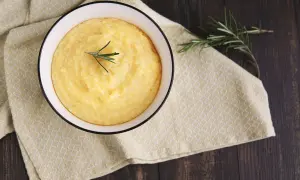 Una ciotola di mazza frissa fumante, guarnita con rosmarino, su un tovagliolo giallo a quadretti.