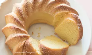 Una soffice torta di ricotta, spolverata di zucchero a velo, tagliata a fette su un piatto bianco.