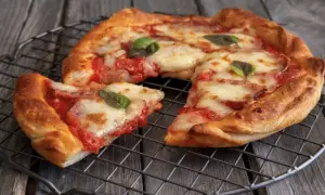 Pizza in friggitrice ad aria, croccante e filante, con pomodoro e mozzarella, guarnita con basilico fresco.