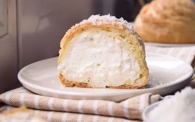 Bignè ripieno di crema soffice, cosparso di zucchero a velo che ricorda fiocchi di neve.
