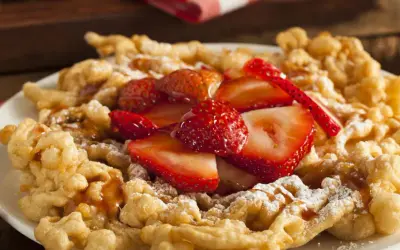 Strauben croccanti, guarniti con fragole fresche e zucchero a velo. Una deliziosa ricetta per un dolce da fiera.