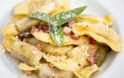 Un piatto di casoncelli alla bergamasca, ripieni e conditi con burro, salvia e pancetta croccante, spolverati di parmigiano.