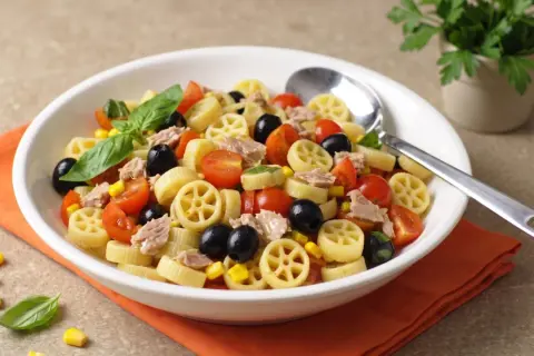 Un piatto invitante di pasta fredda tonno, con pomodorini, olive nere e mais. Perfetta per un pasto estivo.