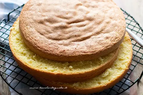 Due dischi di soffice sponge cake dorato, uno sopra l'altro, su una griglia. Perfetti per una torta deliziosa.