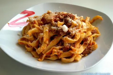 Un piatto invitante di tagliatelle al ragù, condite con abbondante parmigiano grattugiato.