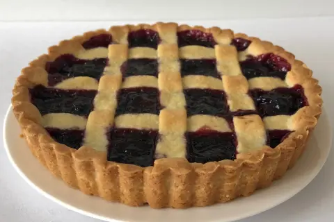 Una deliziosa crostata di marmellata con una griglia di pasta dorata e un ripieno scuro e invitante.