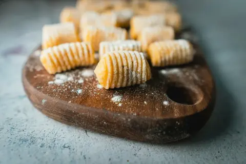 Gnocchi fatti in casa, pronti per essere cucinati. La gnocchi ricetta perfetta è a portata di mano, con questi morbidi e invitanti gnocchi su un tagliere di legno.