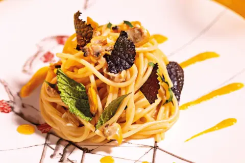 Spaghetti con frutti di mare, guarniti con foglie di menta e scaglie di tartufo. Un'idea su come cucinare la pasta in modo elegante.