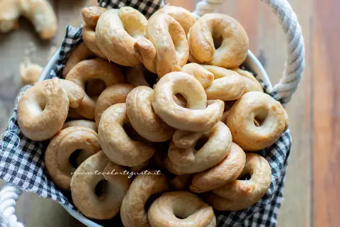 Un cesto pieno di taralli pugliesi ricetta originale, dorati e croccanti, pronti per essere gustati.